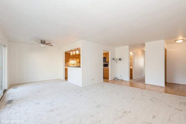 unfurnished living room featuring visible vents, light colored carpet, and ceiling fan