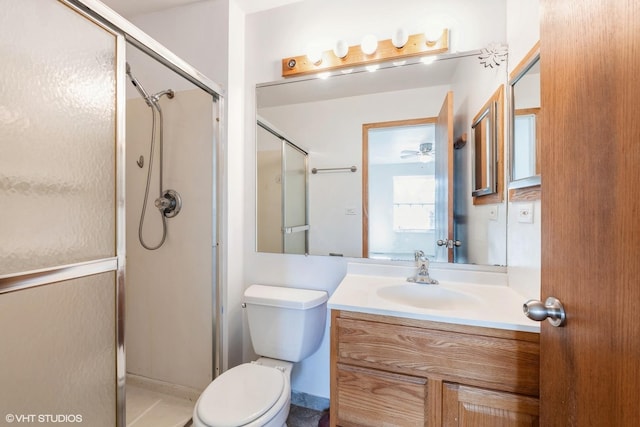 bathroom with vanity, a shower stall, toilet, and ceiling fan