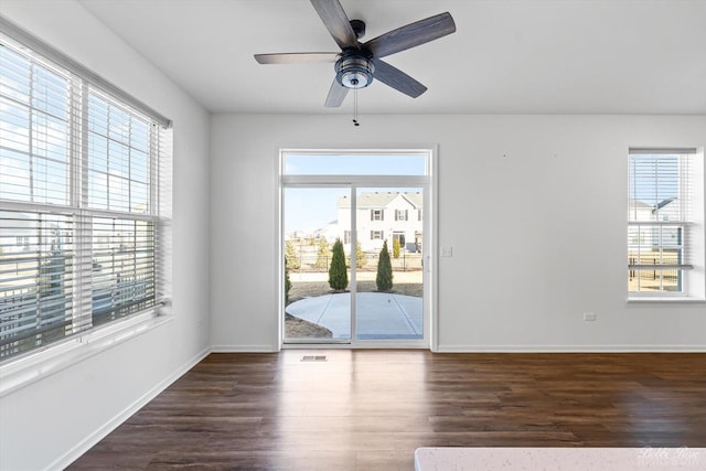 empty room with plenty of natural light, wood finished floors, and baseboards