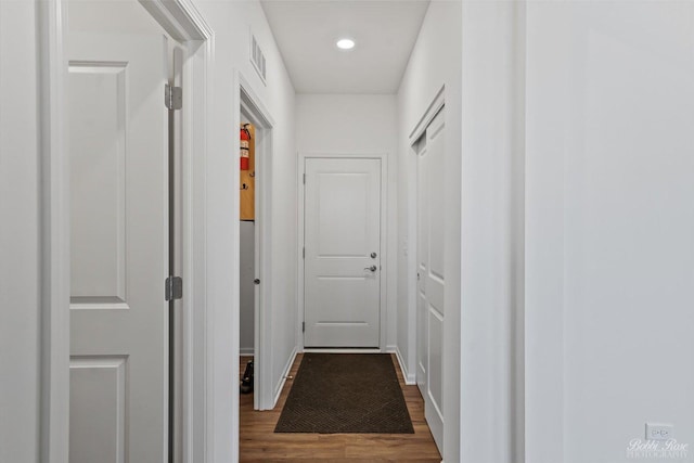 corridor featuring dark wood-type flooring, recessed lighting, and visible vents