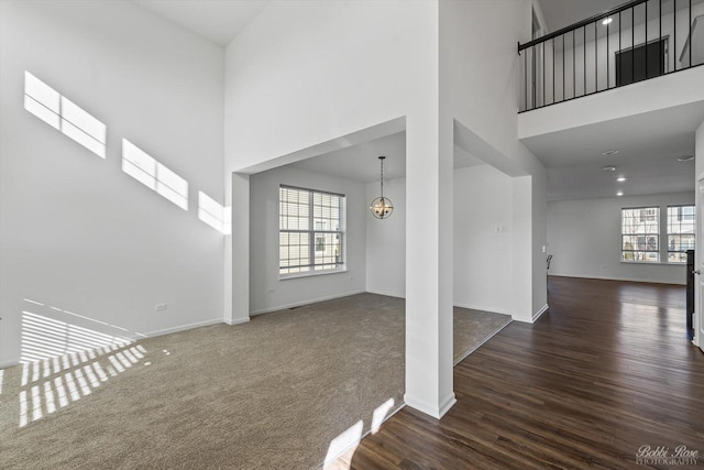 interior space with a healthy amount of sunlight, a towering ceiling, and dark wood finished floors