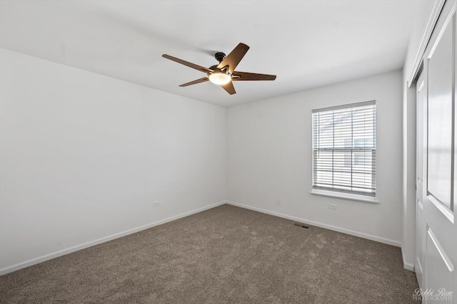 empty room with a ceiling fan, visible vents, carpet, and baseboards