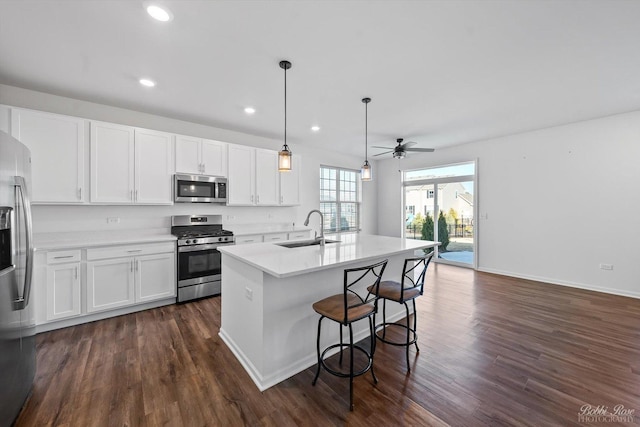 kitchen with light countertops, stainless steel appliances, dark wood-style floors, white cabinetry, and a sink