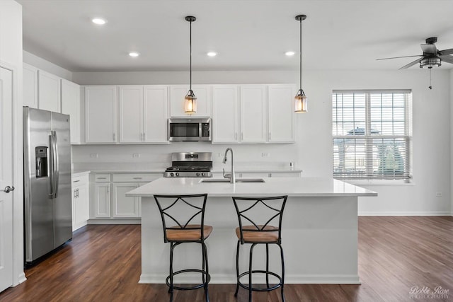 kitchen with dark wood finished floors, a sink, light countertops, appliances with stainless steel finishes, and white cabinetry