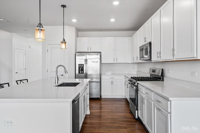 kitchen featuring dark wood-type flooring, a kitchen island with sink, a sink, appliances with stainless steel finishes, and white cabinets