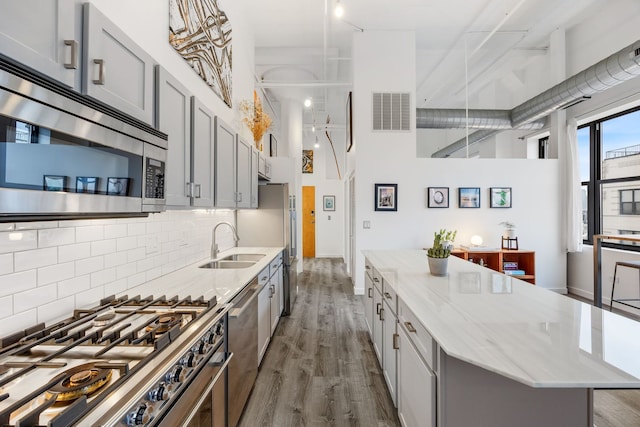 kitchen featuring visible vents, a sink, dark wood-type flooring, appliances with stainless steel finishes, and a center island