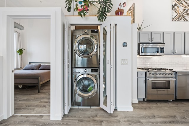 laundry room with stacked washer / drying machine, light wood-style floors, and laundry area