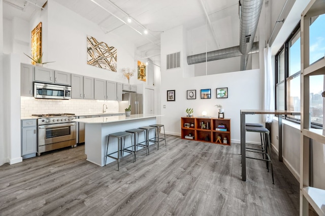 kitchen with stainless steel appliances, visible vents, a towering ceiling, and gray cabinetry