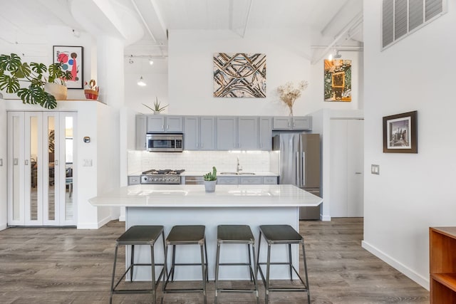 kitchen with visible vents, beamed ceiling, a sink, a kitchen breakfast bar, and appliances with stainless steel finishes