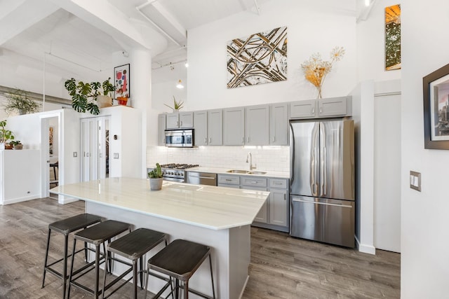 kitchen with gray cabinets, stainless steel appliances, a high ceiling, and a sink