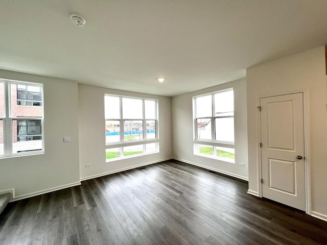empty room with baseboards and dark wood-type flooring