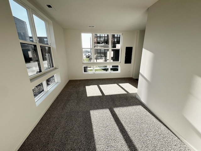unfurnished living room featuring a wealth of natural light, baseboards, carpet floors, and visible vents
