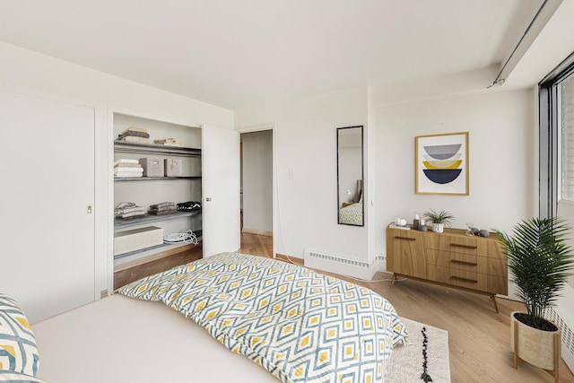 bedroom with wood finished floors and a baseboard radiator