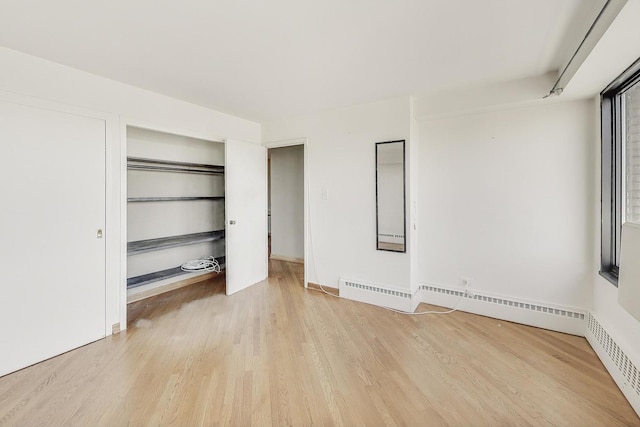 unfurnished bedroom with wood finished floors, a closet, and baseboard heating