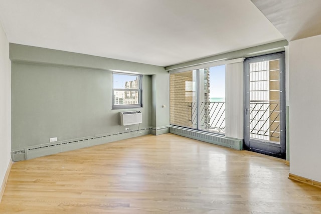 unfurnished room with a wall mounted air conditioner, baseboard heating, and wood finished floors