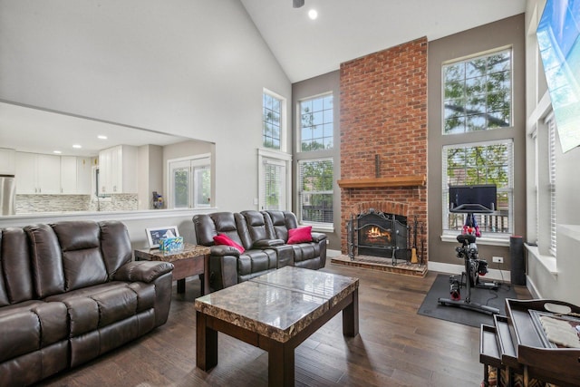 living area with baseboards, high vaulted ceiling, a brick fireplace, and dark wood finished floors