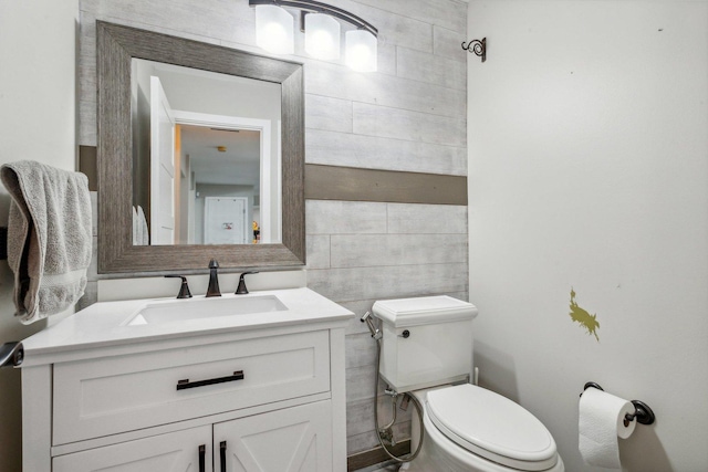 half bath featuring tile walls, toilet, and vanity