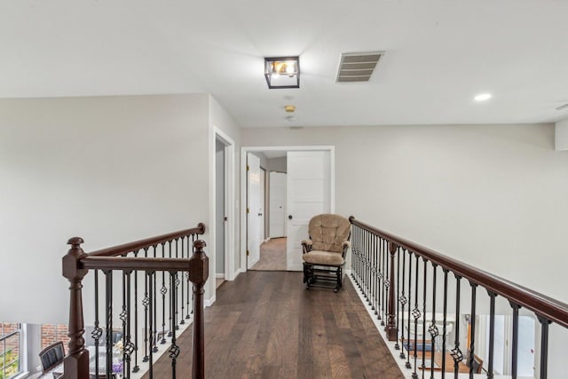 hallway with wood finished floors, visible vents, baseboards, recessed lighting, and an upstairs landing