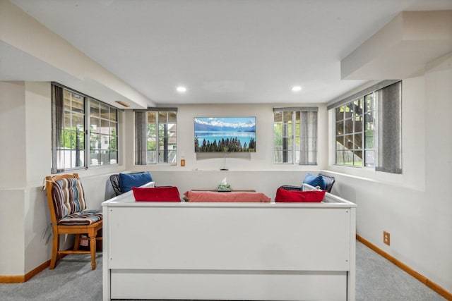 living area featuring plenty of natural light, light colored carpet, and baseboards