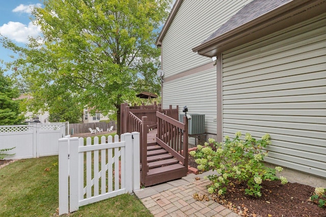 view of side of home featuring central air condition unit, a yard, a deck, and fence