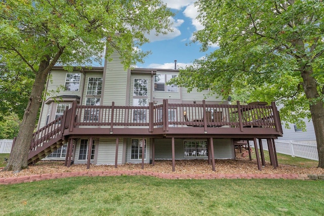 rear view of property with a wooden deck, a yard, and fence