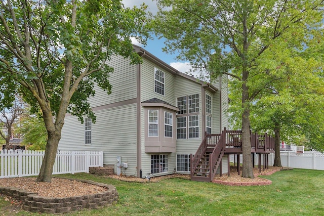 rear view of house featuring a deck, stairway, a lawn, and fence private yard