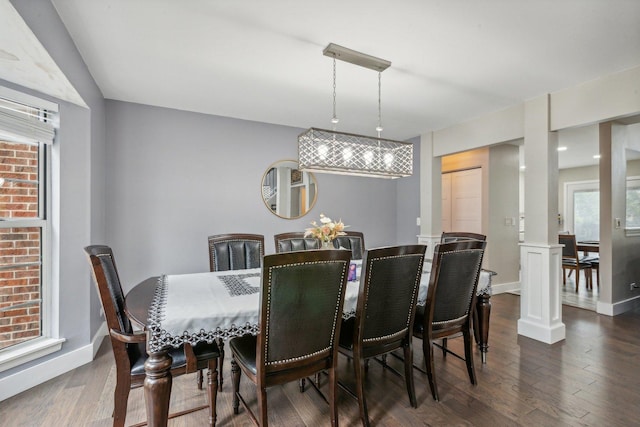 dining area featuring decorative columns, baseboards, and dark wood-type flooring