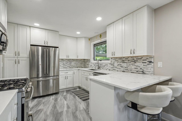 kitchen featuring stainless steel appliances, tasteful backsplash, a peninsula, and white cabinets