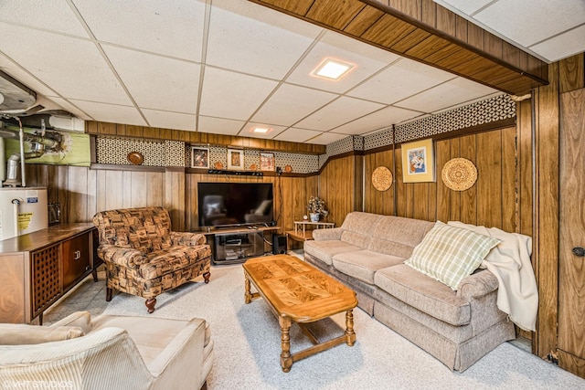 living room with a drop ceiling, carpet flooring, water heater, and wood walls