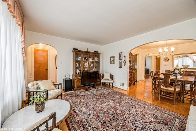 living room featuring a chandelier, arched walkways, and wood finished floors