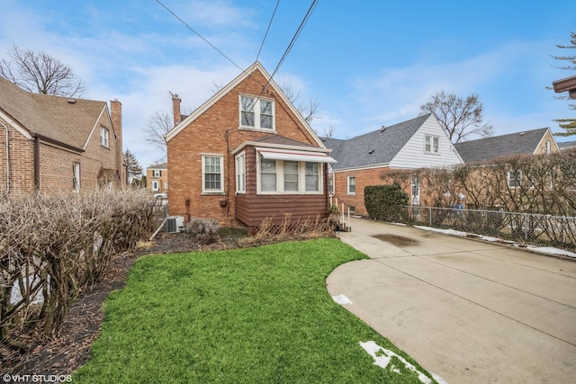 view of front of property with brick siding, fence, a front yard, a chimney, and driveway