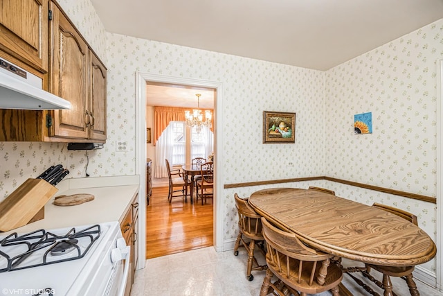 dining room with an inviting chandelier and wallpapered walls