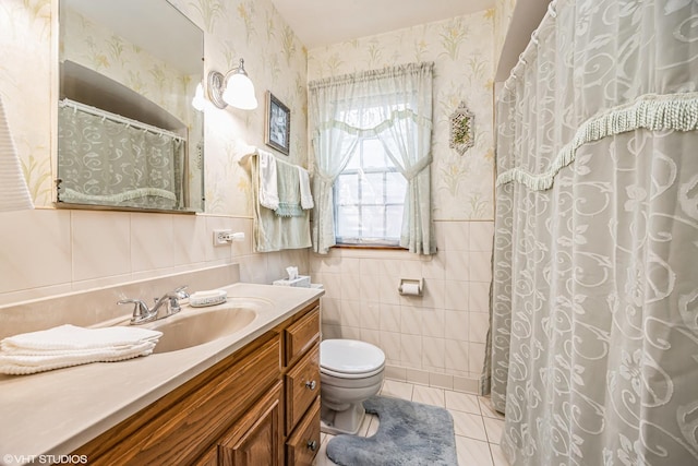 full bath with tile patterned flooring, wallpapered walls, tile walls, toilet, and vanity