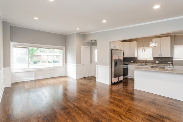 kitchen with a wainscoted wall, appliances with stainless steel finishes, dark wood-style flooring, and a sink