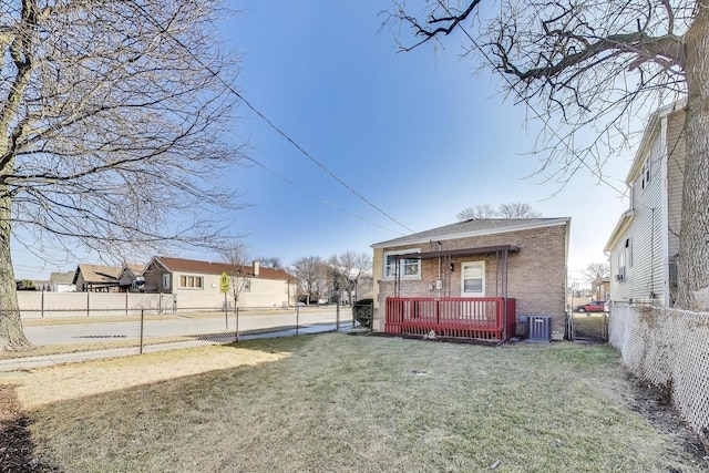 exterior space featuring brick siding, central air condition unit, fence private yard, a yard, and a deck