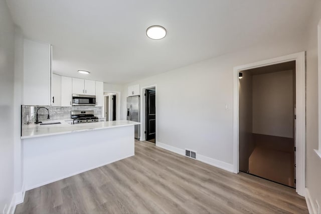 kitchen with visible vents, light countertops, decorative backsplash, stainless steel appliances, and a sink