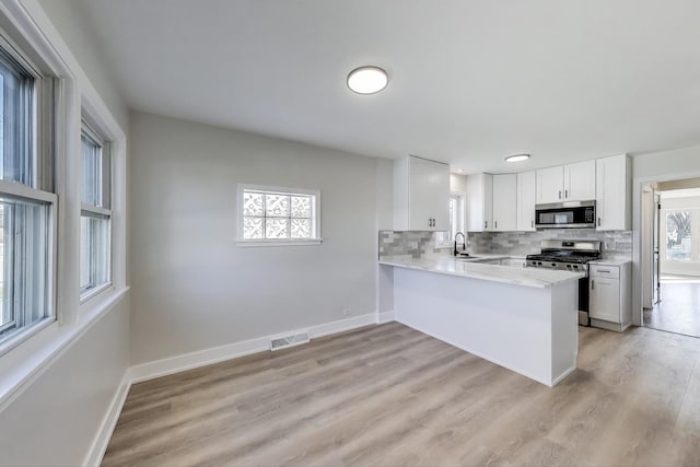 kitchen featuring visible vents, stainless steel appliances, baseboards, and decorative backsplash