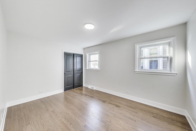 spare room with visible vents, wood finished floors, and baseboards