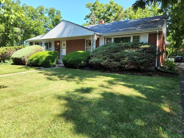 view of front of property with a front lawn, brick siding, and a chimney