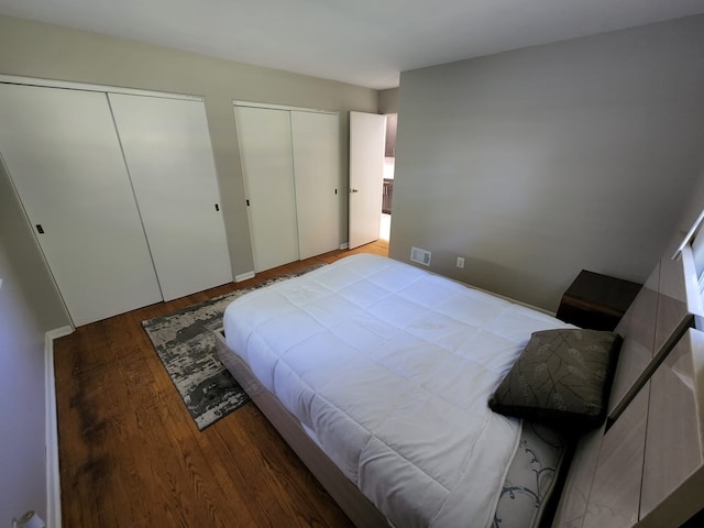 bedroom featuring visible vents, two closets, and wood finished floors