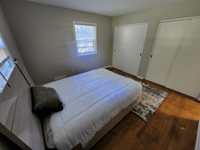 bedroom featuring visible vents, multiple closets, and wood finished floors