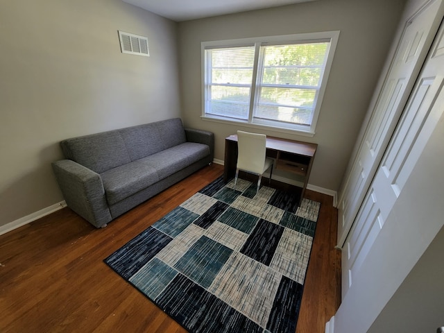 living area with visible vents, baseboards, and wood finished floors