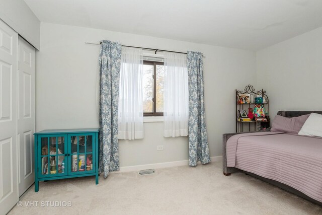 carpeted bedroom featuring a closet, visible vents, and baseboards