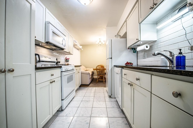 kitchen featuring white appliances, a sink, marble finish floor, dark countertops, and tasteful backsplash