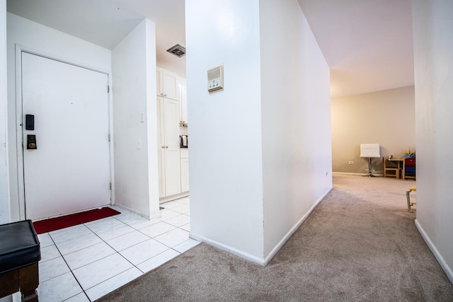 hallway featuring visible vents, light tile patterned floors, light colored carpet, and baseboards