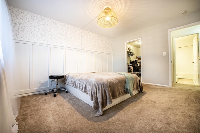 bedroom with wallpapered walls, carpet, wainscoting, a decorative wall, and a spacious closet