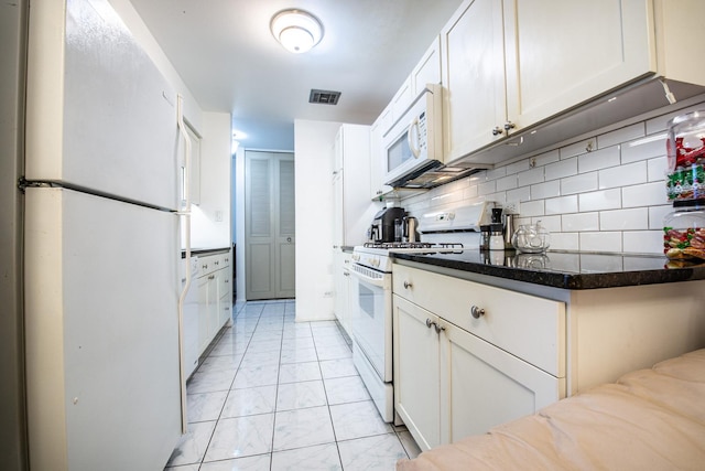 kitchen featuring visible vents, dark stone counters, decorative backsplash, white cabinets, and white appliances