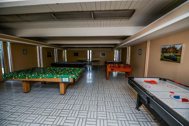 game room with beam ceiling and brick floor