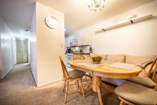 dining space with light colored carpet, baseboards, and a chandelier