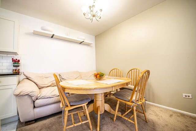 dining area featuring baseboards, light colored carpet, and a chandelier